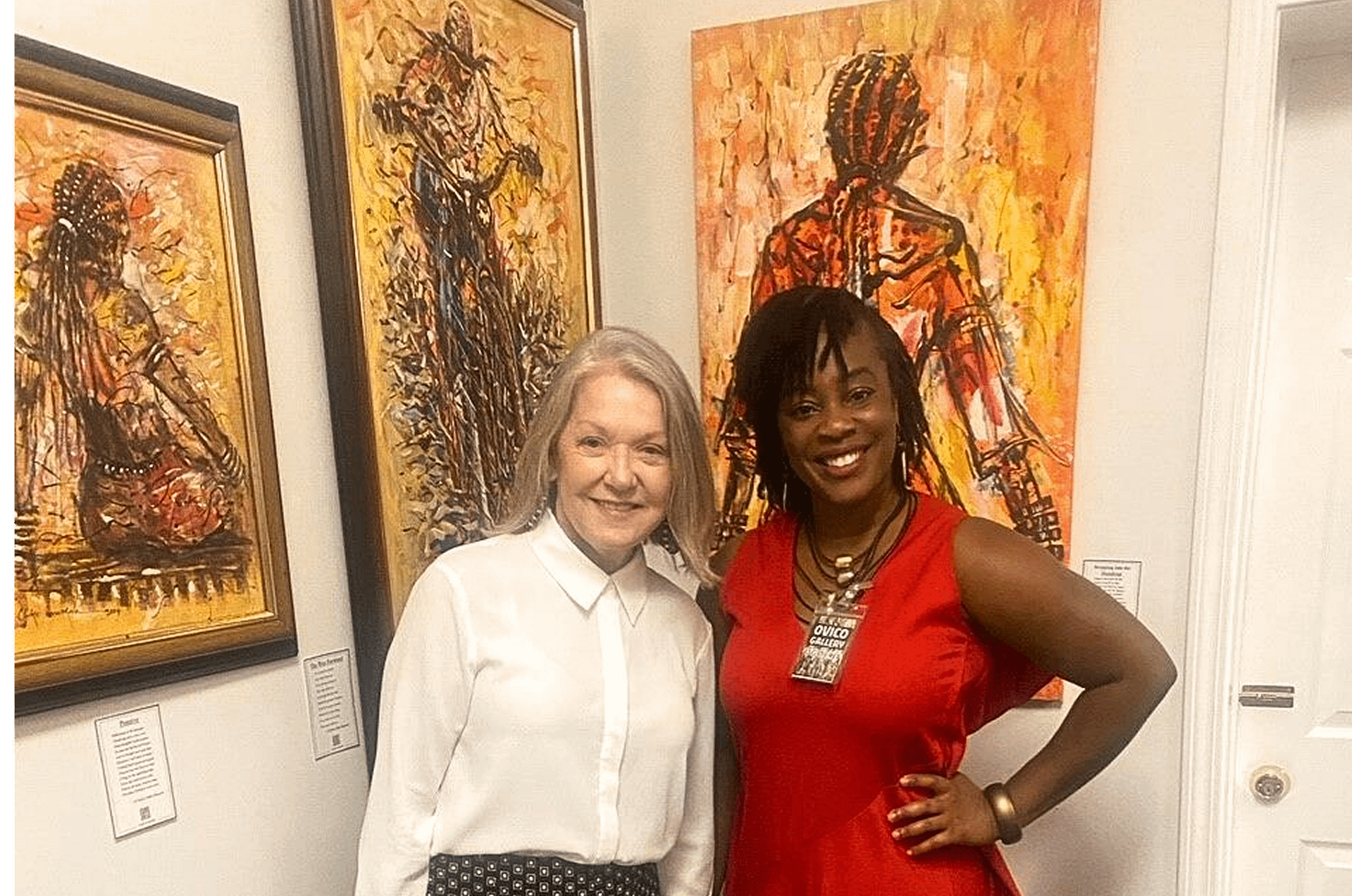 Two women standing in front of expressive African paintings at Ovico Gallery, showcasing vibrant brushwork and storytelling through art and culture.