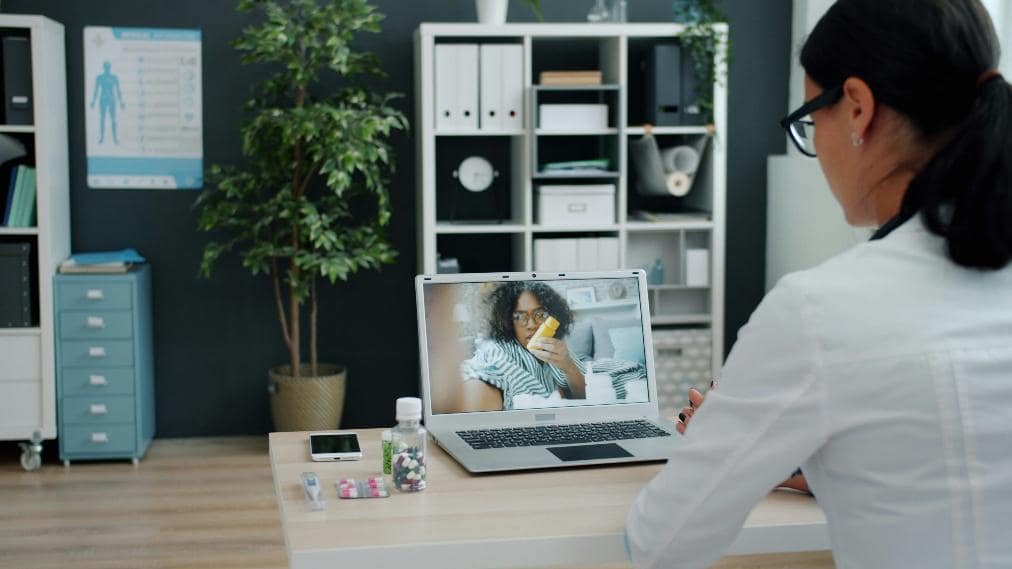Healthcare provider conducting a virtual doctor appointment on a laptop with a patient during an online consultation.