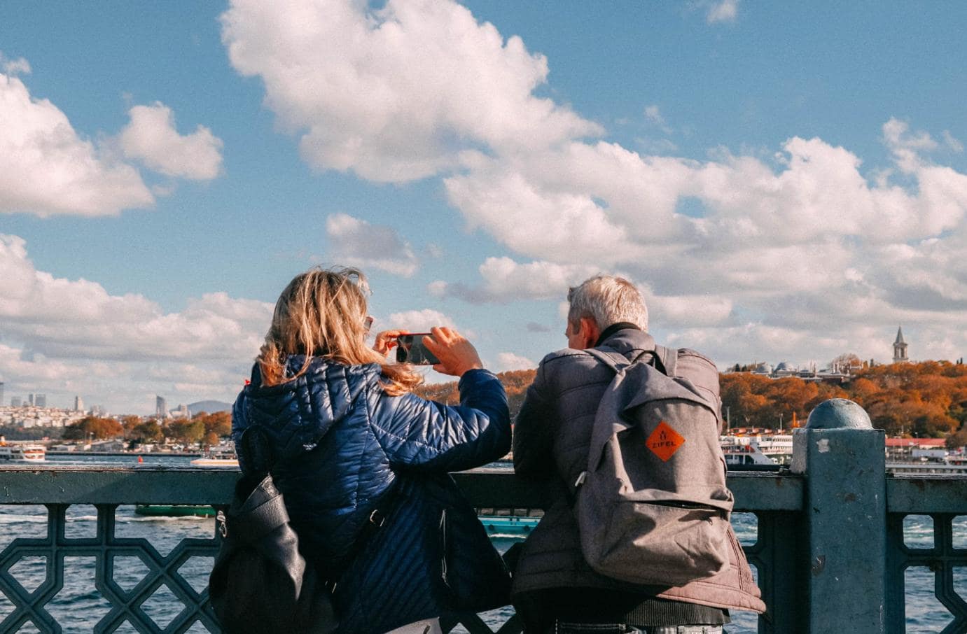 A couple taking photos while sightseeing during a trip.