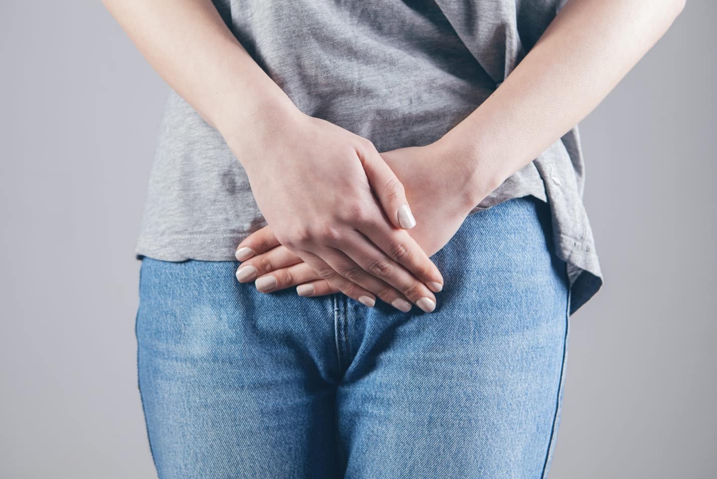 A woman holding her lower abdomen, indicating discomfort