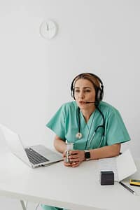 Medical professional wearing a headset during an online doctor visit, providing remote healthcare support through telehealth.