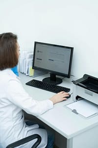 Healthcare professional reviewing patient information on a desktop computer.