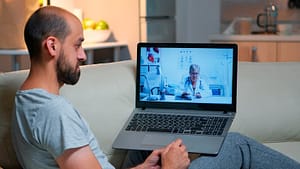 A man speaking with a doctor during an online video consultation.