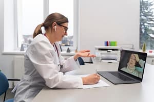 An online doctor speaking with a patient by laptop.