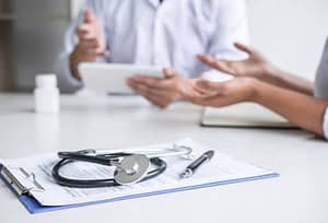 person speaking with doctor over table
