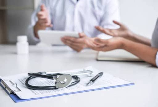 person speaking with doctor over table