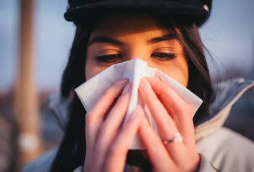 woman blowing nose into tissue