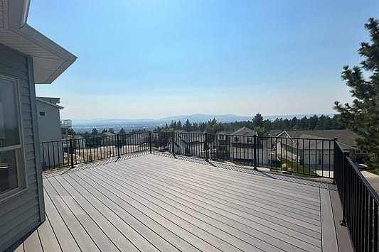 Large composite deck 16 feet off the ground, overlooking the city and houses below with a sunny blue sky in the background.