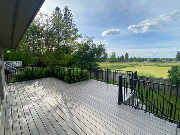 Enjoy the refreshing green surroundings of our custom Timbertech deck in Spokane, Washington. Built with pressure-treated lumber, Timbertech composite decking, and Fortress FE26 handrail. Visit PacificNorthwestDecks.com for more details.