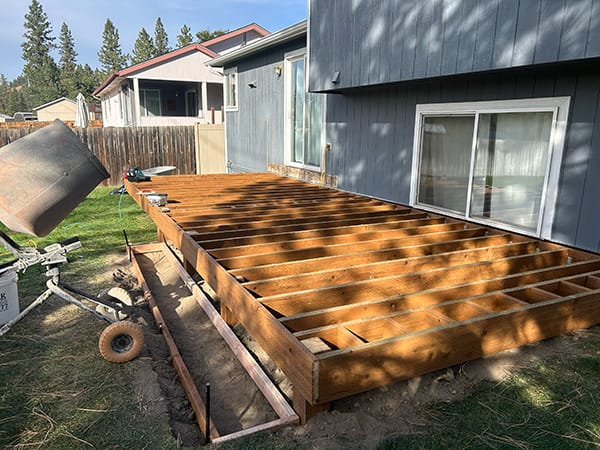 A framed ground-level deck built with pressure-treated lumber, sitting close to the ground.