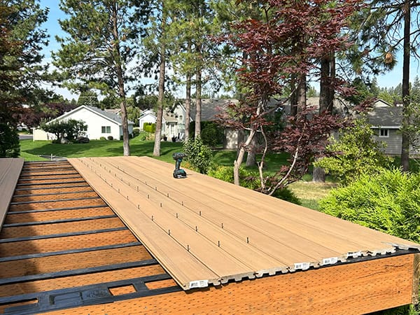 A pressure-treated deck frame with composite deck boards halfway installed.