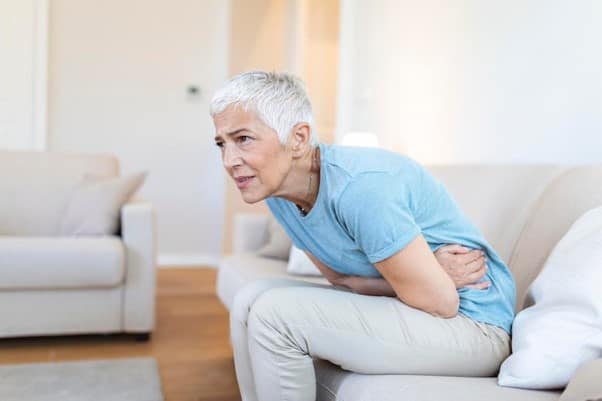 A woman experiencing lower abdominal pain at home.