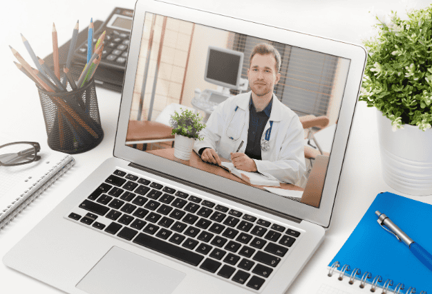 male doctor smiling through laptop