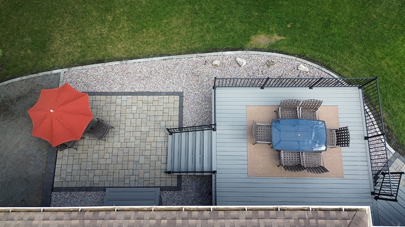 A bird's-eye view of an outdoor living space showcasing a Timbertech composite deck paired with a custom paver patio.
