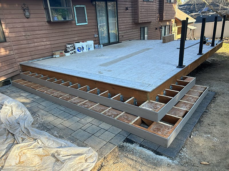 Deck stairs under construction during winter, with installed fascia, framed stringers, and blocking in place, covered with a layer of frost.