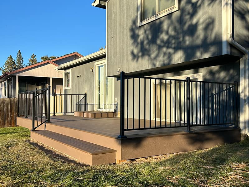 A finished composite deck with a box step, part of the deck is on the ground while the other half is elevated.