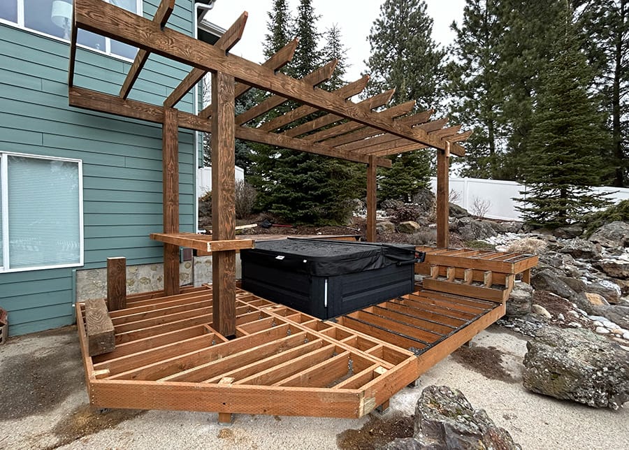 Custom multi-level deck with a bar, built-in bar stool chairs, pergola, and hot tub in Spokane, Washington.