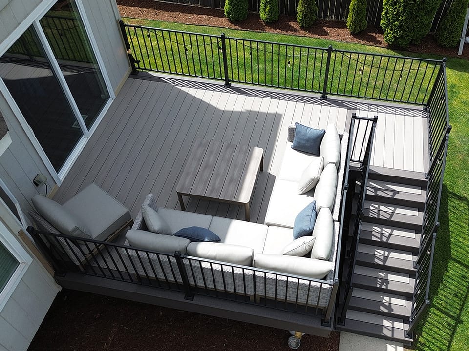 A smaller deck with an L-shaped couch and coffee table used as an outdoor living space.