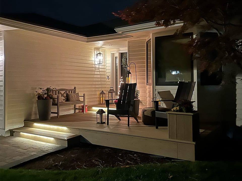 Front porch with a matching planter box and custom step lighting at night.