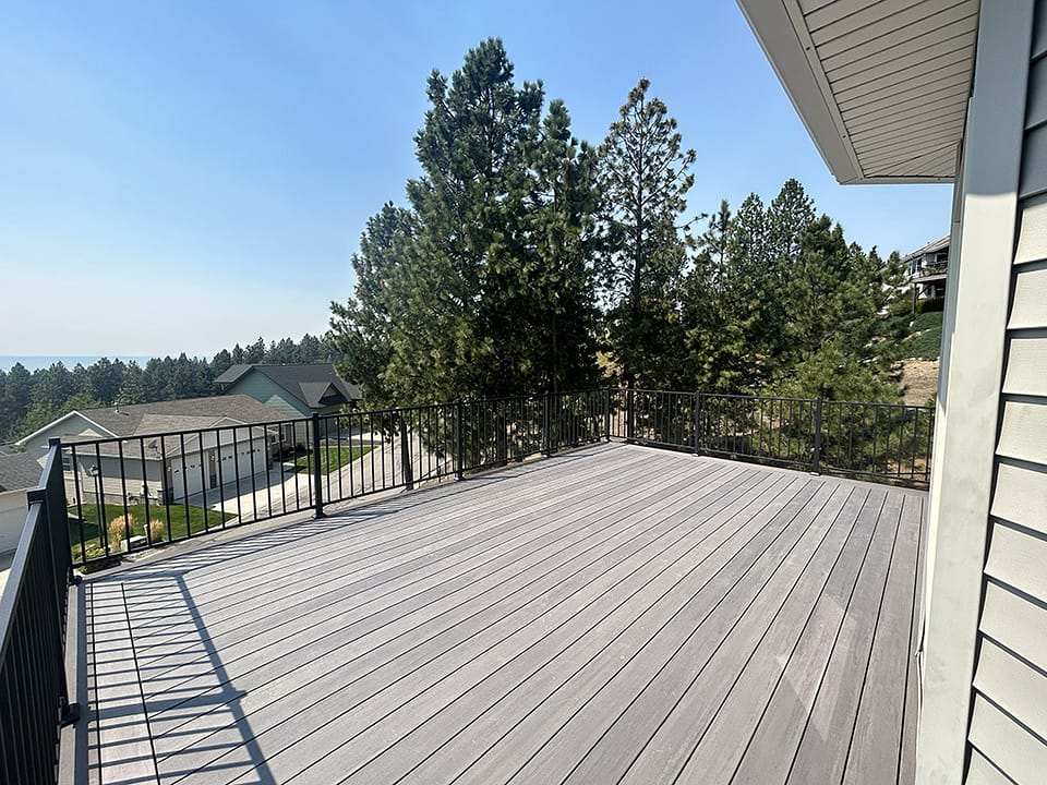 Large composite deck overlooking the suburbs and surrounded by pine trees.