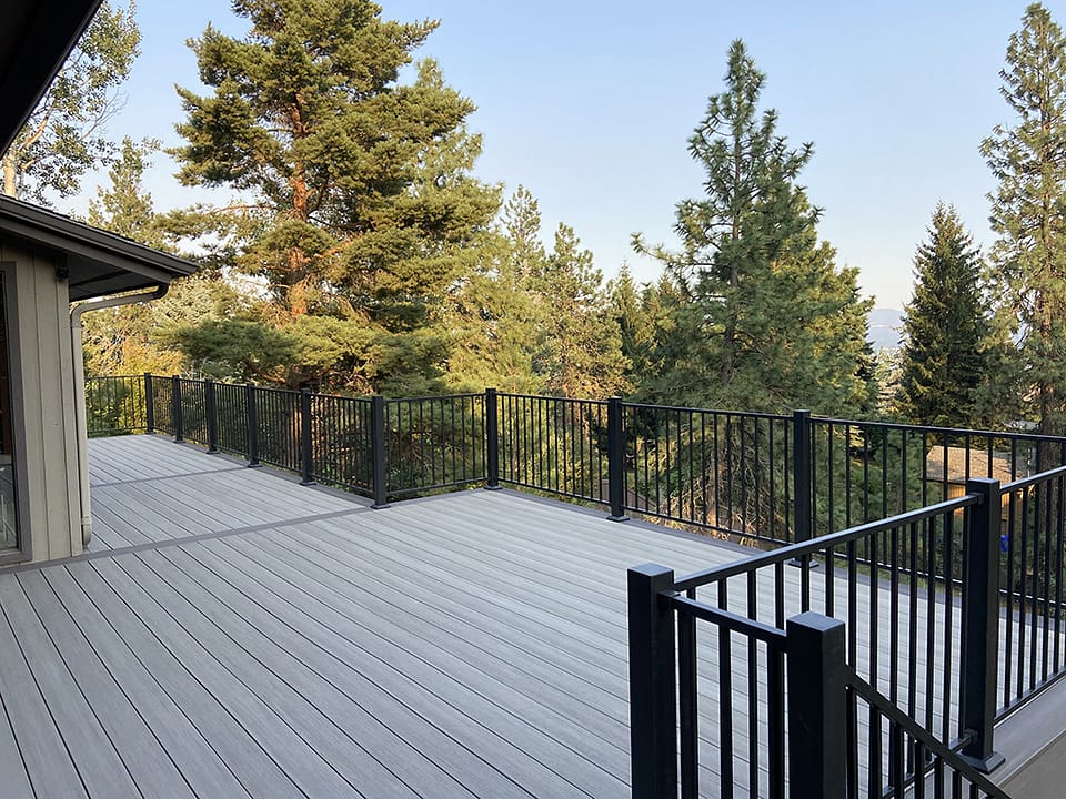 Large custom deck spanning the back of a home with pine trees in the background.