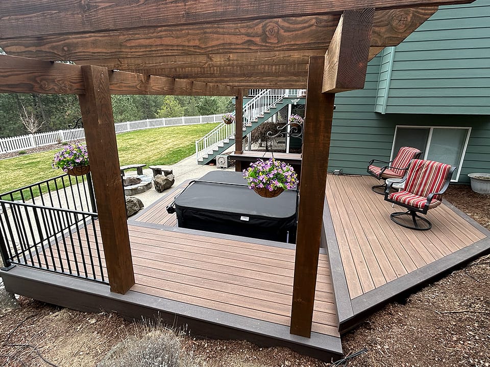 Multi-tier deck with seating areas, a hot tub, and a towering pergola overhead.