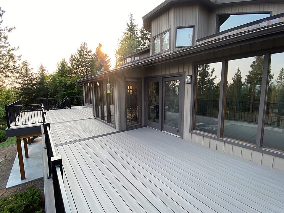 Large deck spanning across the back of a home with sunlight shining above, creating a scenic view.