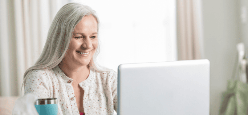 older woman smiling looking at laptop