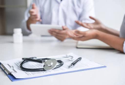 person speaking with doctor over table