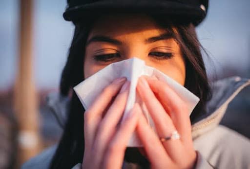 woman blowing nose into tissue