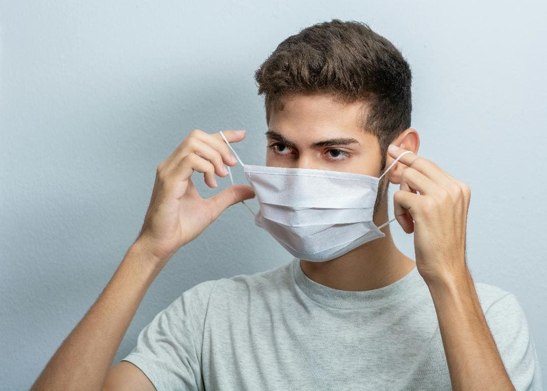 Young man adjusting a face mask.