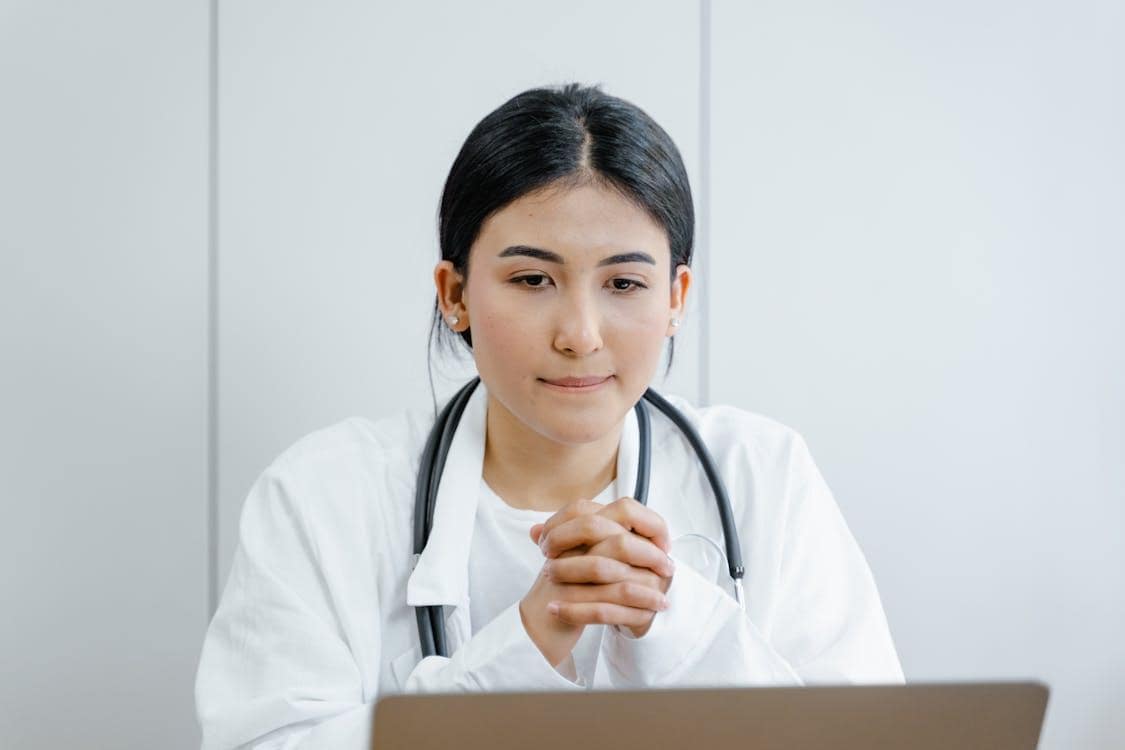 Doctor sitting in front of a laptop providing an online consultation for UTI symptoms