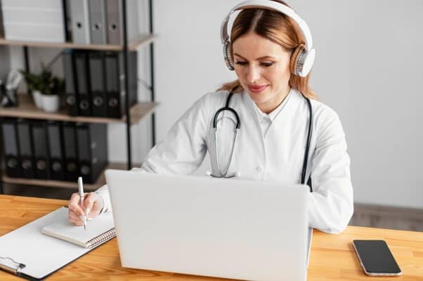 An online doctor taking notes during a virtual appointment.