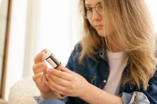 A woman holding an empty prescription medication container.